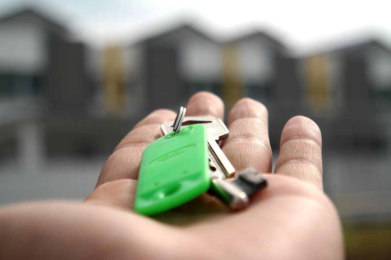 The Mortgage Centres Branches | Keys to a new home sitting in the palm of a hand with blurred houses in the background