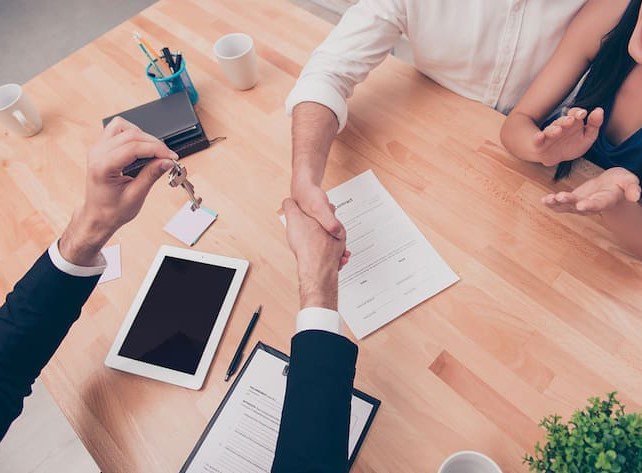 Home reversion plans | Shaking hands over paperwork at a desk