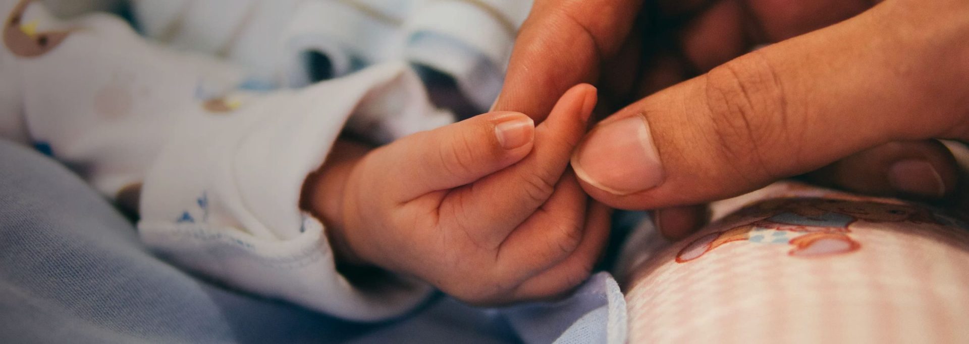 Income protection | Hand holding a newborn baby's hand